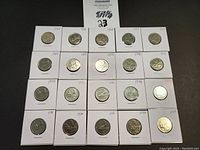 20 Canadian quarters from various years in 1960s and 1970s displayed individually in coin holders showing obverse and reverse sides in some cases.