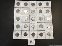 Image showing 25 Canadian quarters each in a white holder with years and notes written, including several commemorative coins.