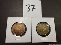 Two Canadian commemorative one-dollar coins in white cardboard holders, labeled 37. One coin commemorates the Saskatchewan Roughriders 100th anniversary (2010), the other commemorates the 100th Grey Cup game (2012).