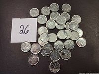 Photo of 35 Canadian commemorative dimes with a label showing the quantity '26'. Coins arranged on a dark surface.