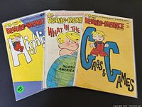 Photo shows three vintage Dennis the Menace comic books from the 1970s with colorful covers and titles visible.