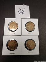 Four 2009 Canadian Montreal Canadiens loonies placed on black background each encased in white cardboard coin holders with a numbered label '36' above them.