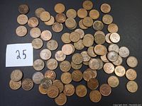 Overview photo showing 85 Canadian pennies spread on a surface, some grouped with a number label '25'. Shows mixed condition and types, including commemorative coins.