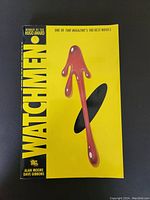 Front cover of Watchmen graphic novel featuring yellow background and blood drop arrow symbol.