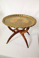 Angled view of round engraved brass top plate on wooden foldable base with brass feet