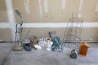 Full view of the garden decor lot showing bird statues, ceramic animal figurines, plant supports, birdhouses and decorative signs.