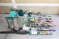 Full view of whole lot showing folding bench, watering cans, assortment of tools, nets, and fabric.