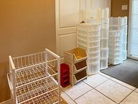 Photo showing multiple storage drawer towers and containers arranged in a row by wall, some towers partially disassembled