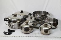 Photo showing the entire cookware set including pots, saucepans, steamer insert, lids, and extra handles arranged on white background