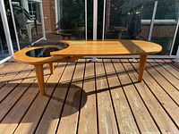 Full angled view of the elongated top tier and circular lower tier insert, showing three tapered legs and wood finish.