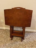 Folded TV trays stored in the wooden stand with handle on top