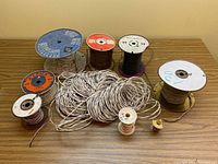Overview of various wire spools in different sizes and colors on a wooden table.