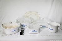 Photo of all five Corningware pieces in the lot showing lids, sizes, and blue cornflower design on white ceramic