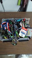 Two plastic boxes filled with assorted lanyards featuring different colors and printed text