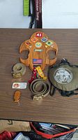 Wooden Boy Scout wall plaque with attached patches, multiple fabric belts with Boy Scout emblem belts, metal canteen with scout trail cover and strap, and leather keychain with Scout emblem