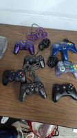 All seven controllers arranged on a brown table showing condition and color variations