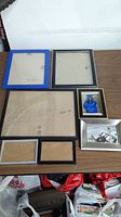 Seven assorted picture frames displayed on a table, showing details and condition.