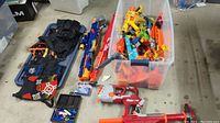 View of large lot of Nerf blasters, tactical vest, darts and accessories.