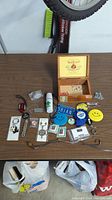 Overview of all miscellaneous pins, keychains, patches, and items arranged on a table with a wooden cigar box labeled 'Don Tomas' open and containing additional items.