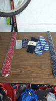 New clothing accessories including ties, socks, and flip-flops laid on a wooden surface.