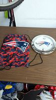 Photo of the Patriots wall clock and matching drawstring bag placed on a table