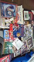 Overview of baseball memorabilia lot including newspapers, trading card folders, game programs, collectible folders, photos, and game items.