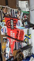 Top view showing assorted sports memorabilia on a wood surface including ESPN college pennants, patches, cards, and booklets scattered and overlapping