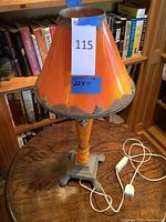 Front view of antique lamp with orange Bakelite-like shade and painted metal base on wooden table, label showing size 22 x 11 inches