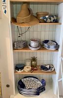 Overall view of shelf showing straw visor hat, basket, whale decor, ceramic dishes and accents