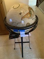 Front view of the globe on the black metal tripod stand showing size and overall condition.