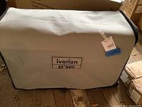 Soft-sided carrying case labeled 'ivation EZ BED' with dimensions noted on a blue sticker as 21 x 16 x 31 inches, containing the inflatable bed folded down for storage.