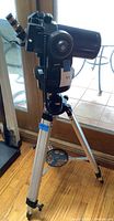 Side view of blue telescope mounted on black equatorial mount with silver tripod