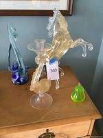 Overview of all four glass artworks: horse figurine, dolphin candlestick, swan basket, and pear