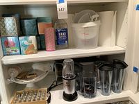 Shelf with Magic Bullet blender, hand sanitizer, paper towels, tissue boxes, containers and baking items