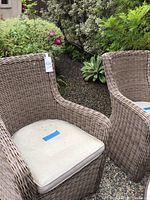 Front-left angle view showing one wicker patio chair with cushion