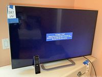 Front view of the 42 inch Vizio TV powered on showing no signal message, with a remote placed in front of the TV.