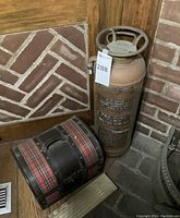Extinguisher and tartan pipe box side by side on brick and wood floor