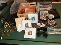 Full lot view showing all items on green surface including brass hangers, trinket box, sunglasses, ashtray, small decor, and frames