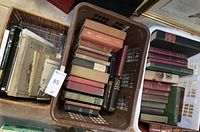 Two baskets showing a mix of older hardcover books in a wicker basket and assorted volumes in a brown plastic crate