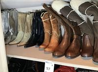 Overview of six pairs of women's boots on shelf: metallic silver, beige and black fringe, two-tone tan, brown riding, shearling-lined brown