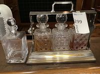 Overall lot view: silver-plated rack holding three cut glass decanters and additional square decanter