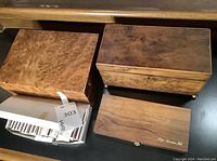 Three wooden boxes including one labeled as cigar service kit. Boxes have natural wooden tones and finishes.