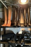 Four pairs of boots displayed on two shelves: tan knee-high, black knee-high, black lace-up knee-high, black suede ankle