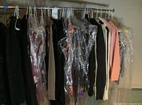 Full clothing rack with plastic garment bags removed