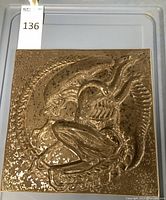 Front view of square relief tile showing raised Xenomorph image and bronze finish