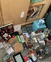 Photo showing the entire collection including Grill Express box, Tiffany boxes, Minnie Mouse plush, costume jewelry, photo frames, and various small gift items scattered on floor.