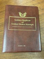 Closed brown leather-like cover of the book with gold embossed text and emblem.