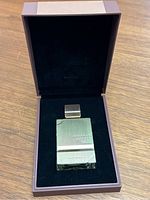 View of Haramain Amber Oud men's cologne gold edition bottle inside original lined box on wooden surface, bottle rectangular and gold-tone.