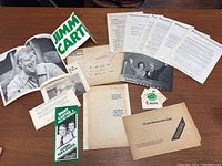 Overview of contents showing posters, pamphlets, envelopes, documents, autographed photo and campaign button spread on table.