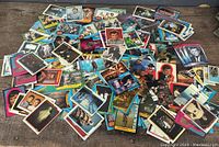 Large assortment of mixed trading cards spread out on a wooden surface showing multiple franchises including Star Wars and Star Trek.